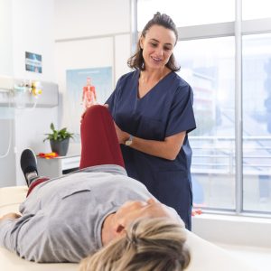 female physiotherapist and senior woman with artificial leg stretching