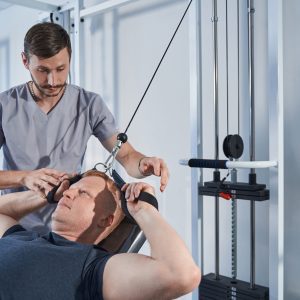 Handicapped man stretches strap on strength-training machine